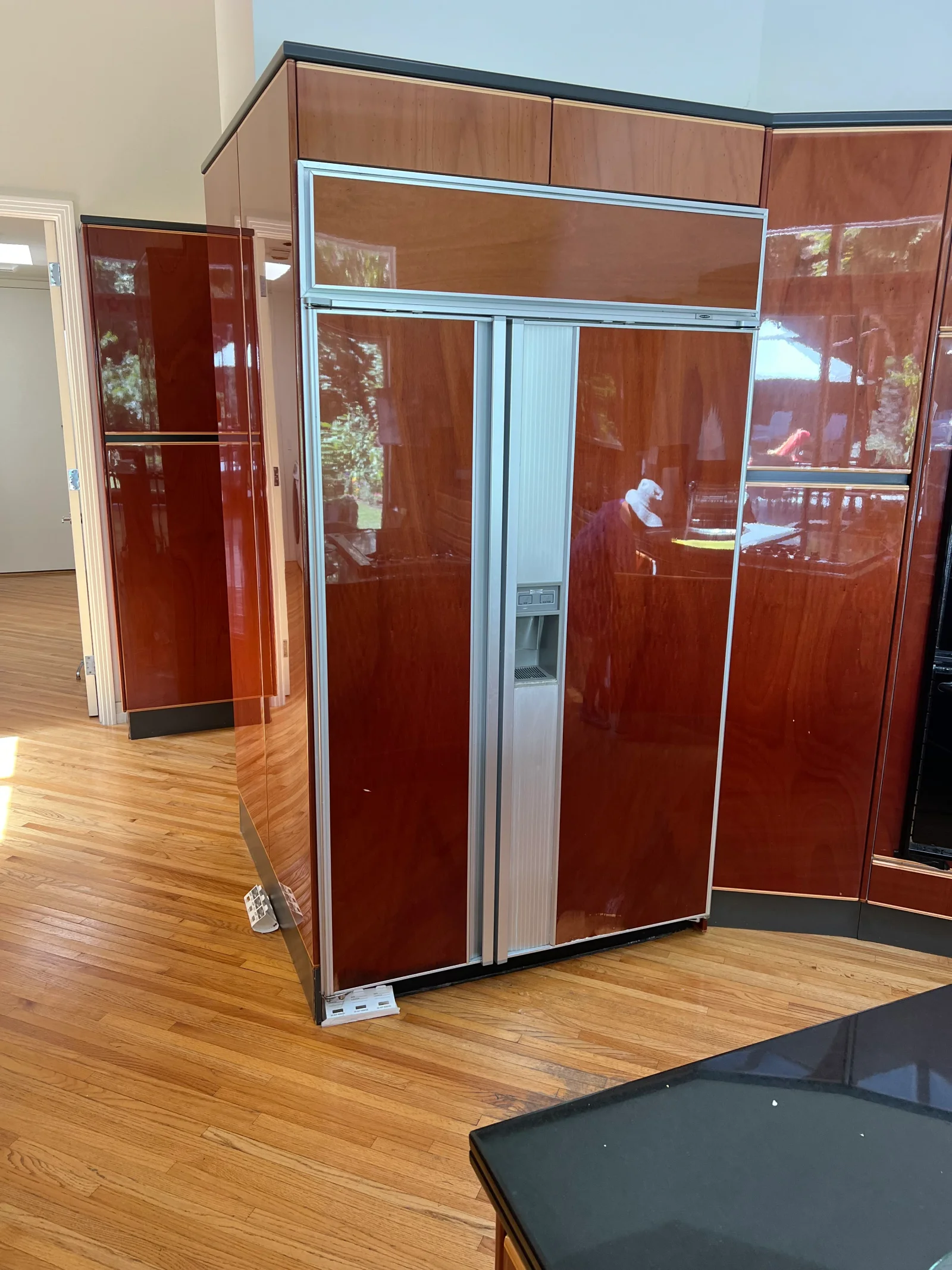 Built-in refrigerator with burgundy glass doors and stainless steel frame on hardwood floor