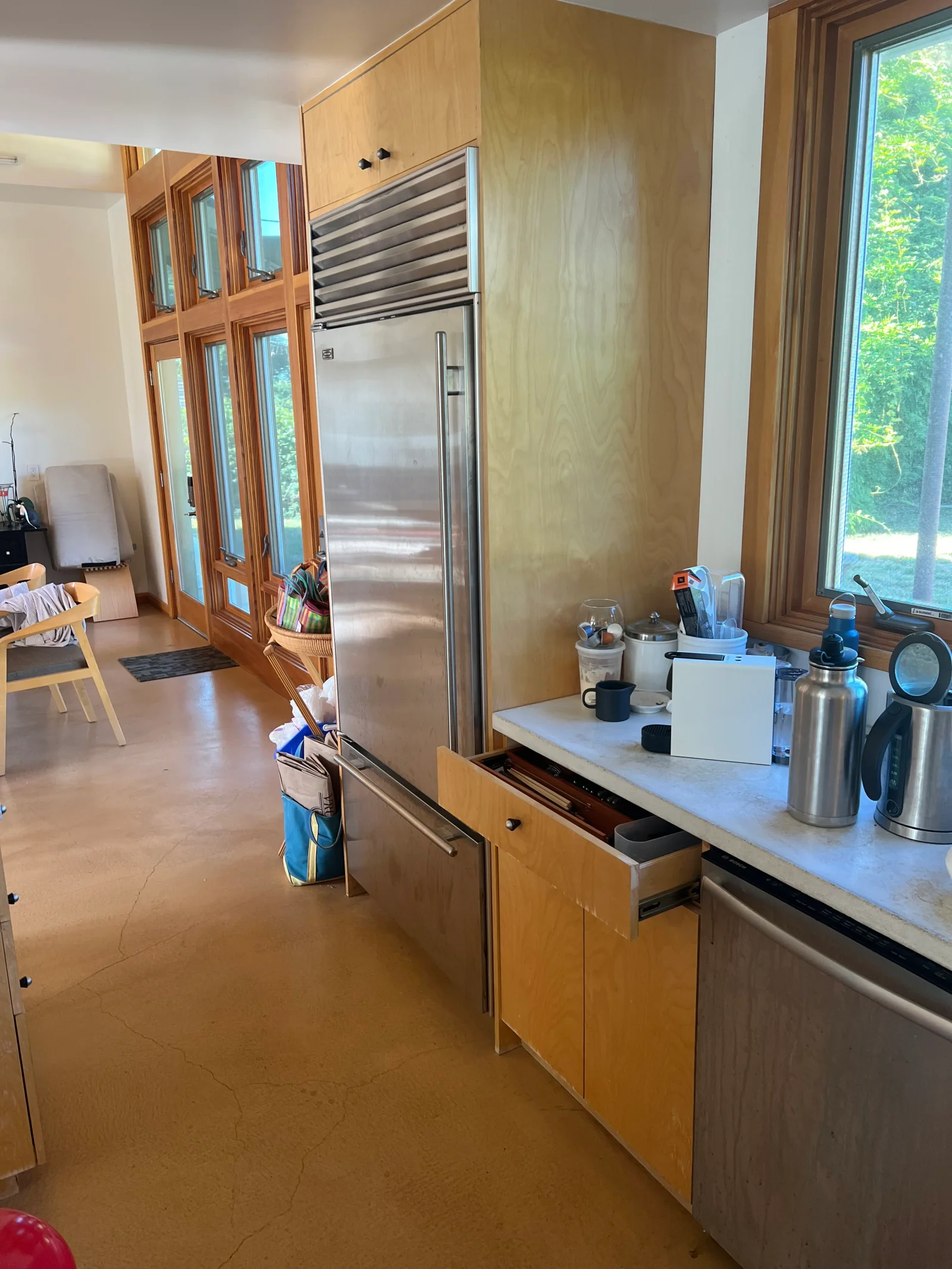 Stainless steel refrigerator and range hood installed in kitchen with wood cabinetry and marble counters