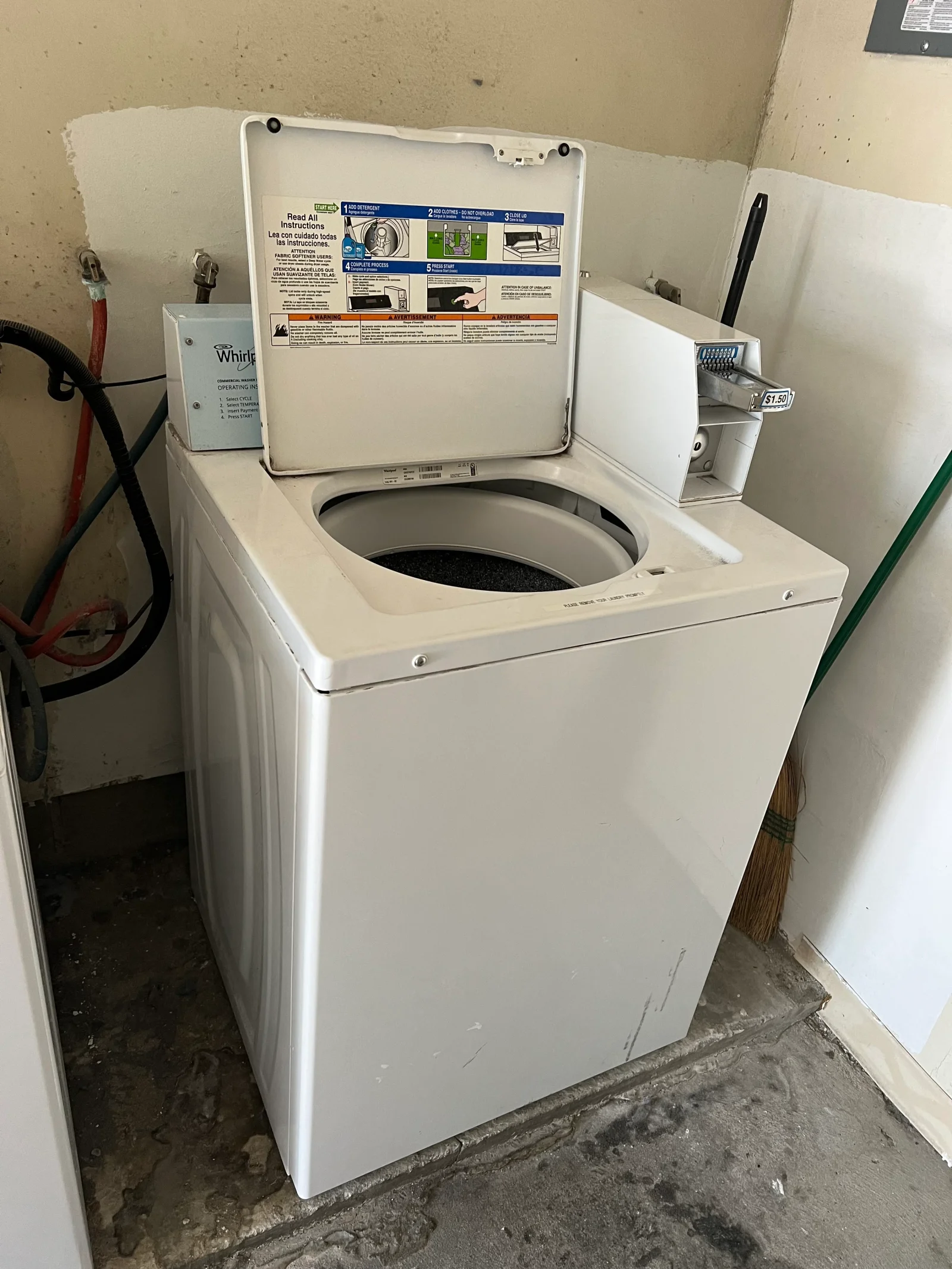 White Whirlpool top-load washer with open lid and instruction manual displayed on lid