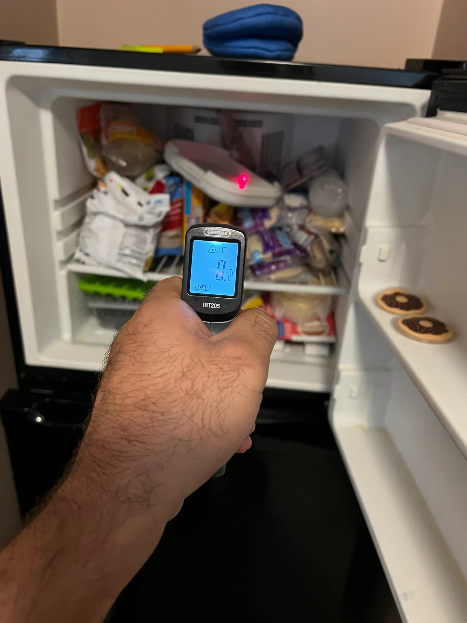Infrared thermometer measuring refrigerator interior temperature during diagnostic assessment
