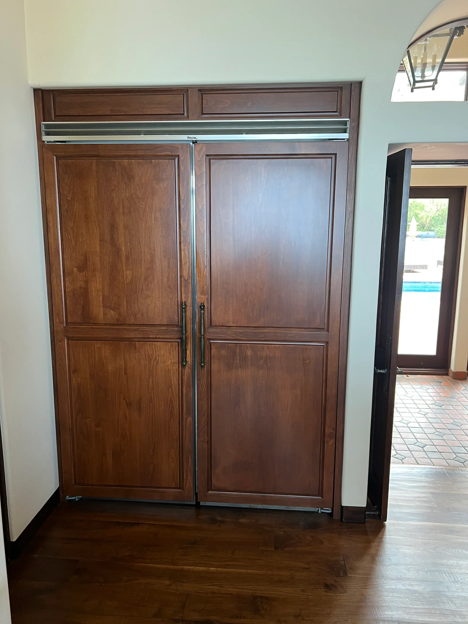 Built-in refrigerator with walnut wood panel doors and stainless steel trim installed in kitchen