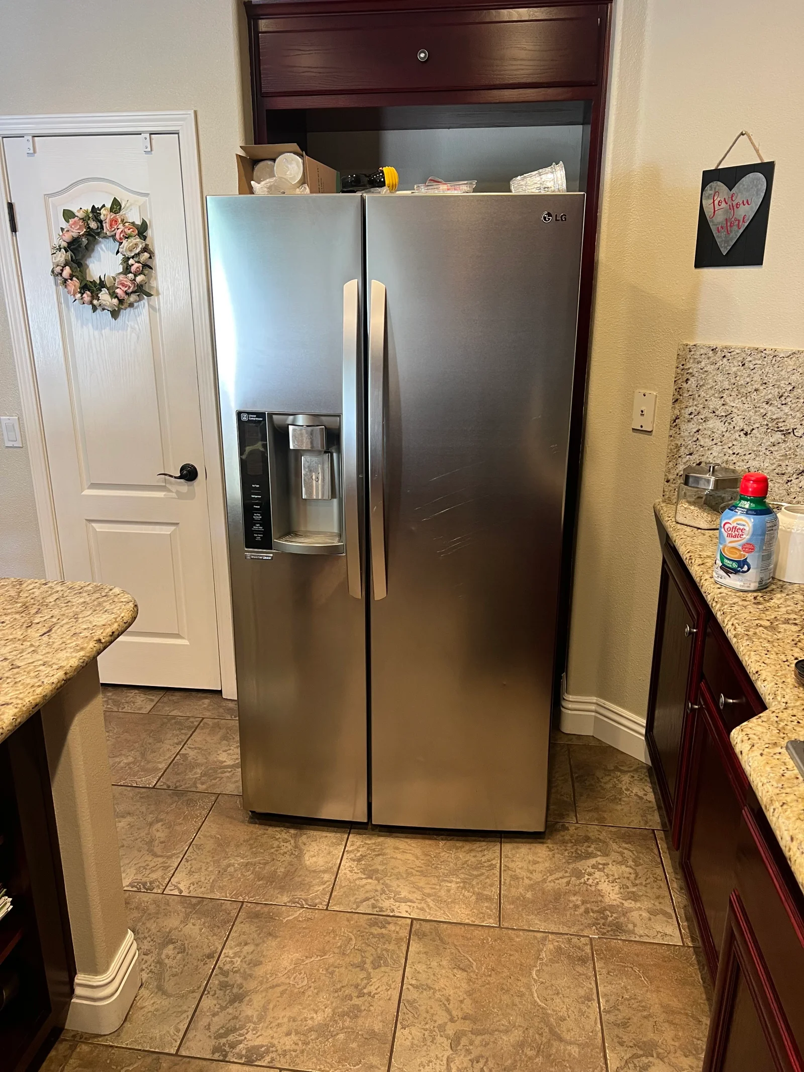 Stainless steel LG side-by-side refrigerator with ice/water dispenser installed in kitchen