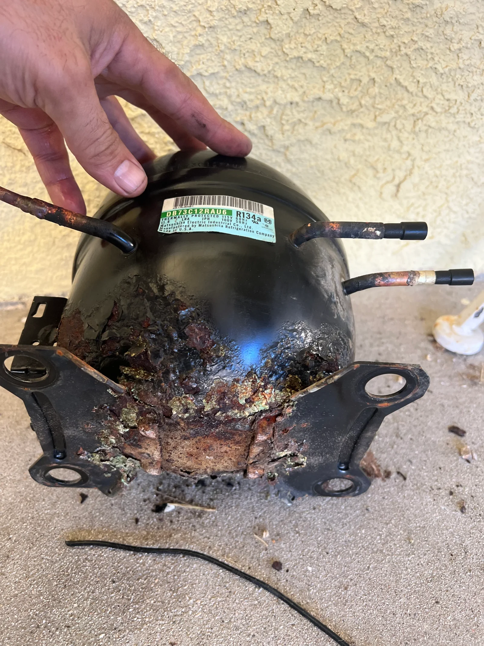 Corroded refrigerator compressor with rust buildup on casing and copper tubing connections