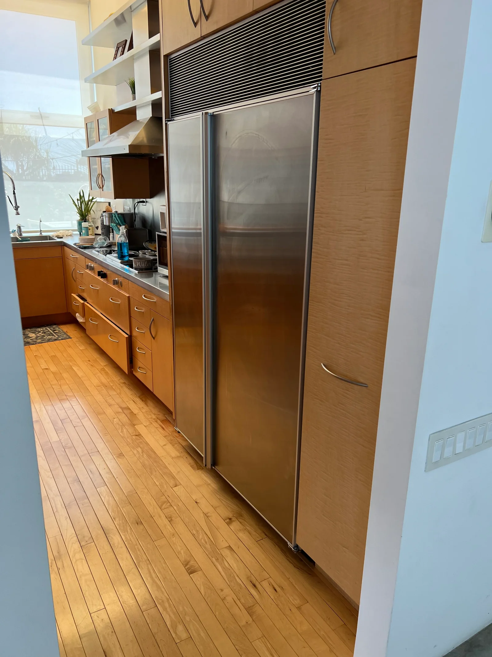 Stainless steel side-by-side refrigerator installed next to wood cabinetry in kitchen