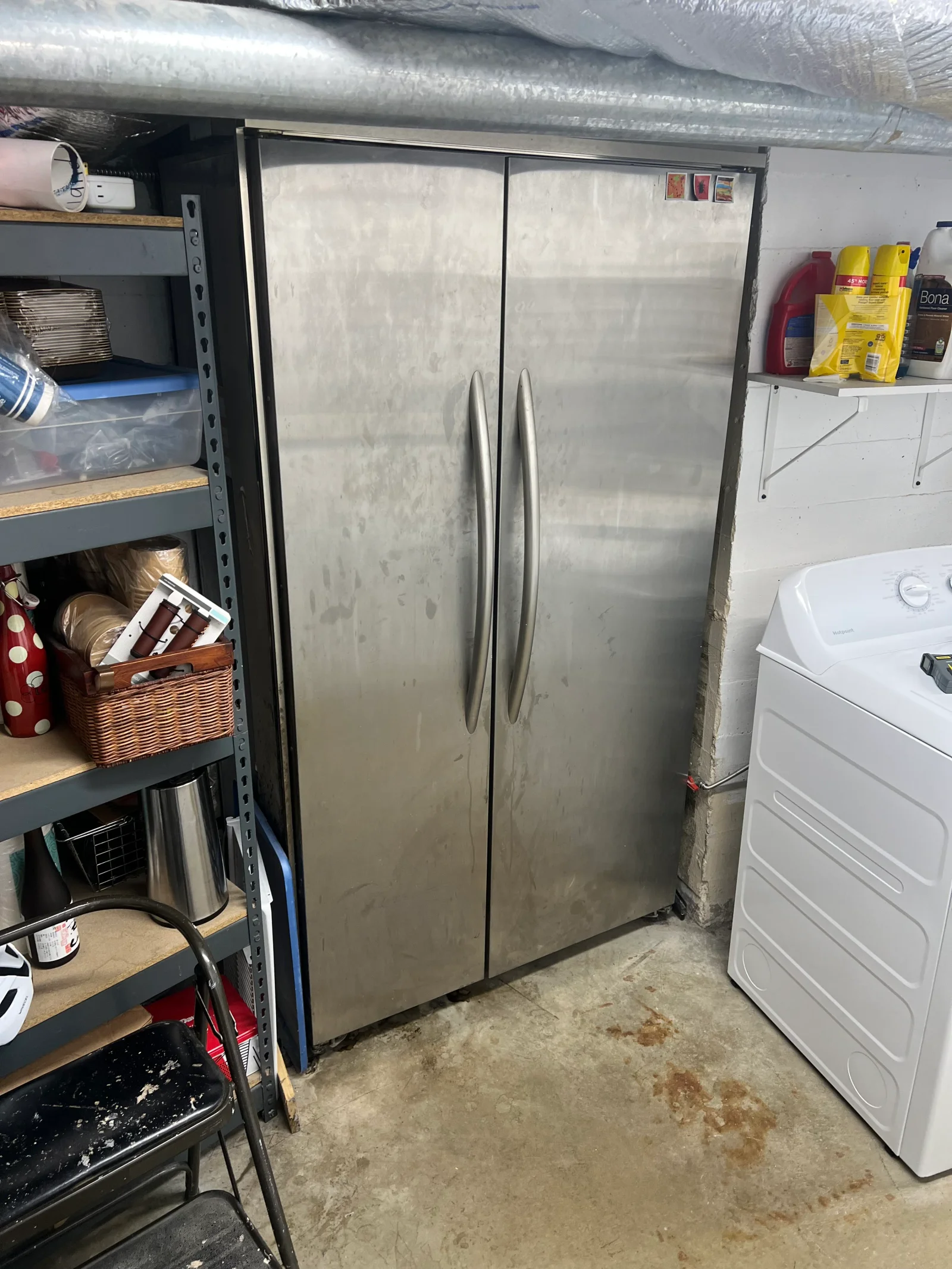 Stainless steel side-by-side refrigerator with dual handles in garage workspace