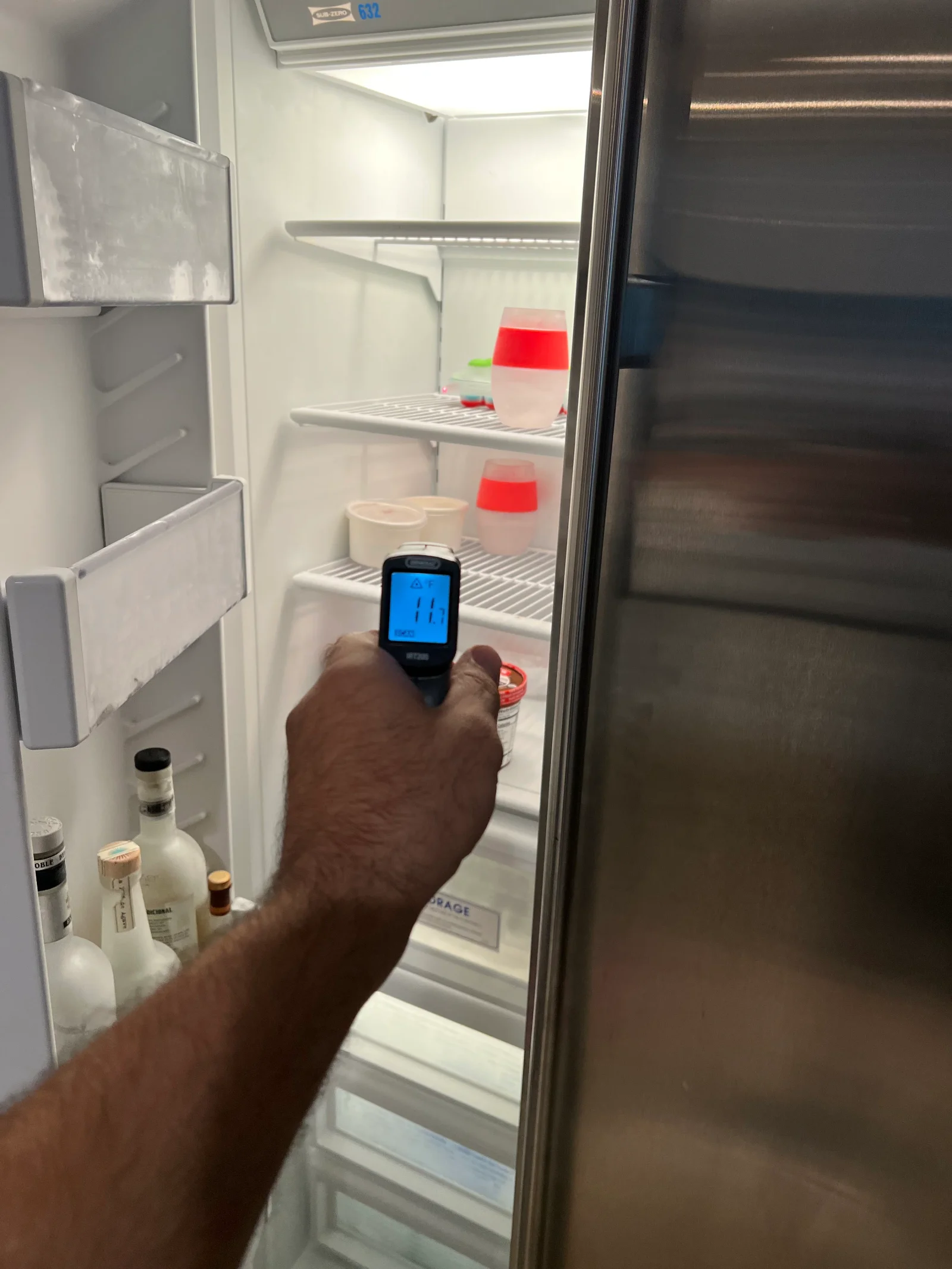 Digital thermometer reading 41°F inside refrigerator with wire shelves and storage containers