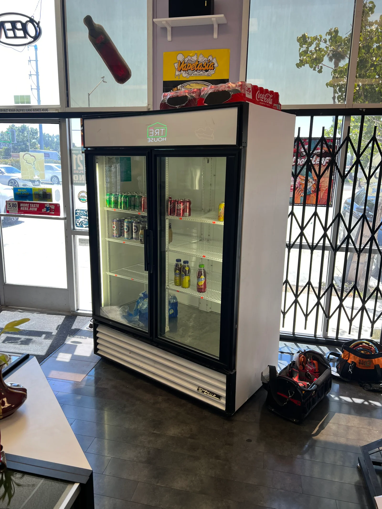 Two-door commercial glass refrigerator with black frame and shelving installed in retail space