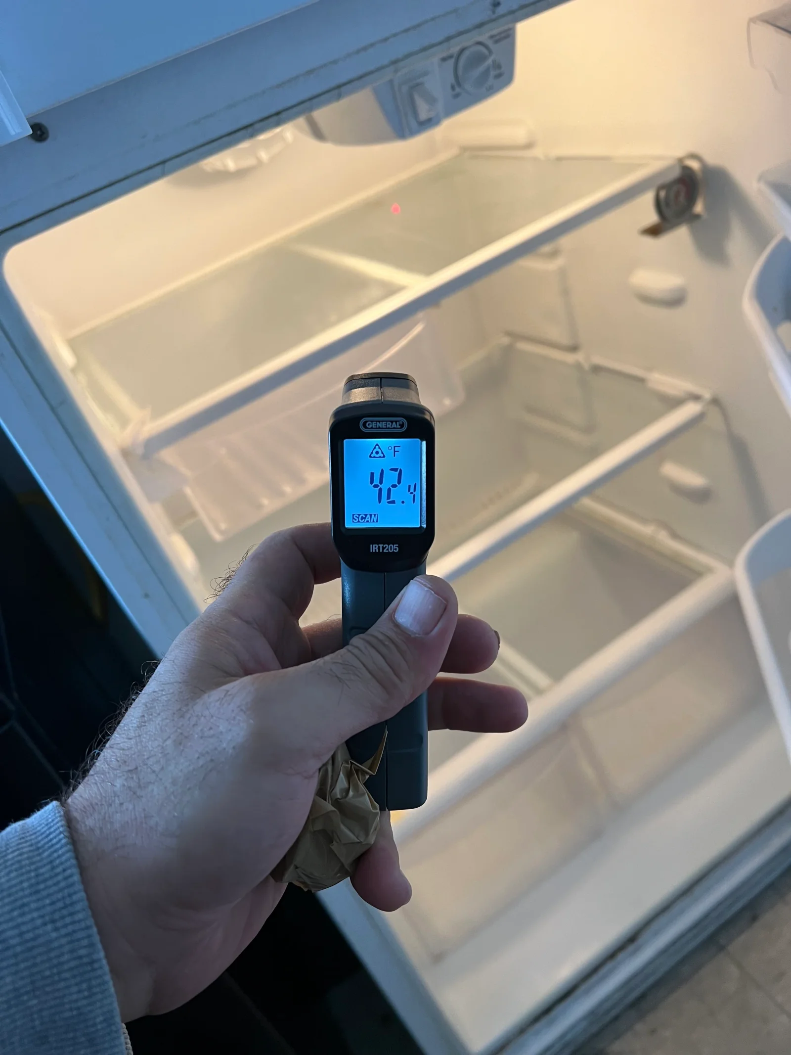 Infrared thermometer reading 42.4°F on white plastic cooler interior with divided compartments