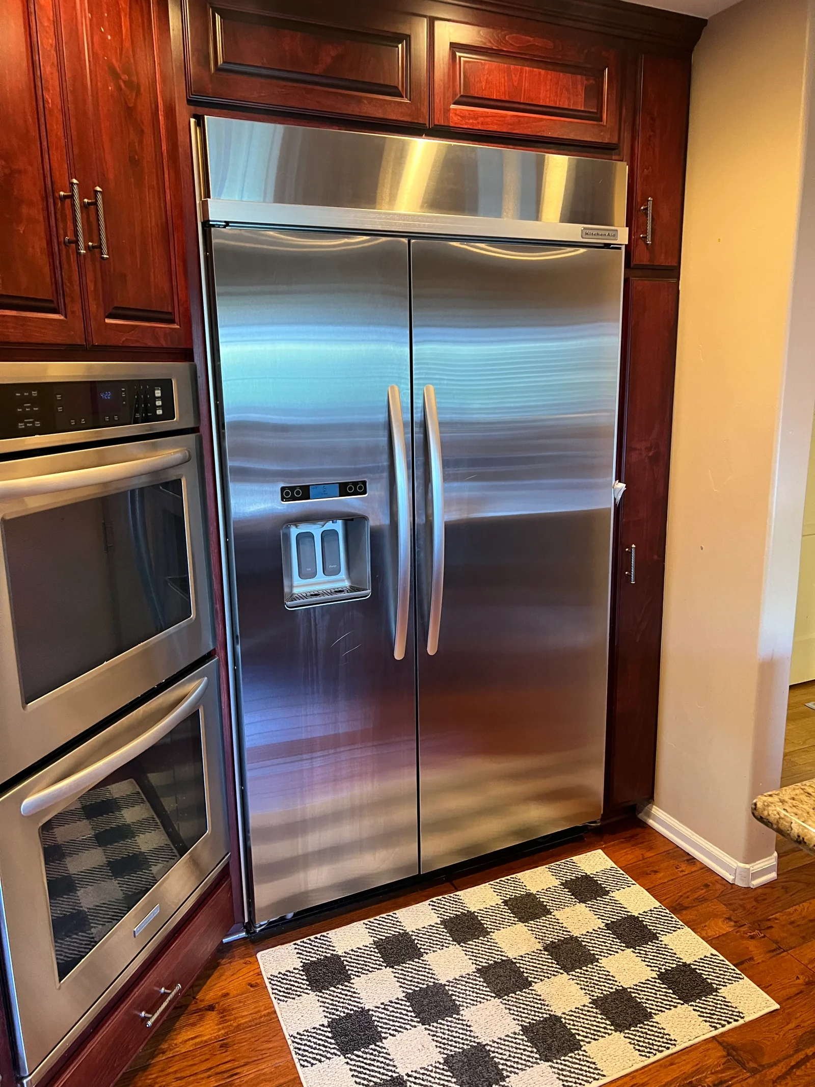 Stainless steel side-by-side refrigerator with ice dispenser in cherry wood kitchen cabinetry